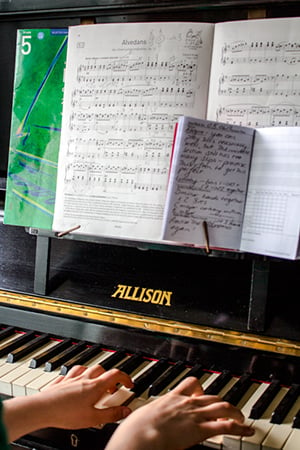 A photo of hands playing a piano, following sheet music.