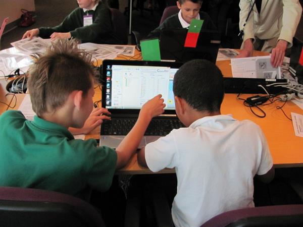 A photo of two pupils at a desk, sharing a screen and working on a task together.